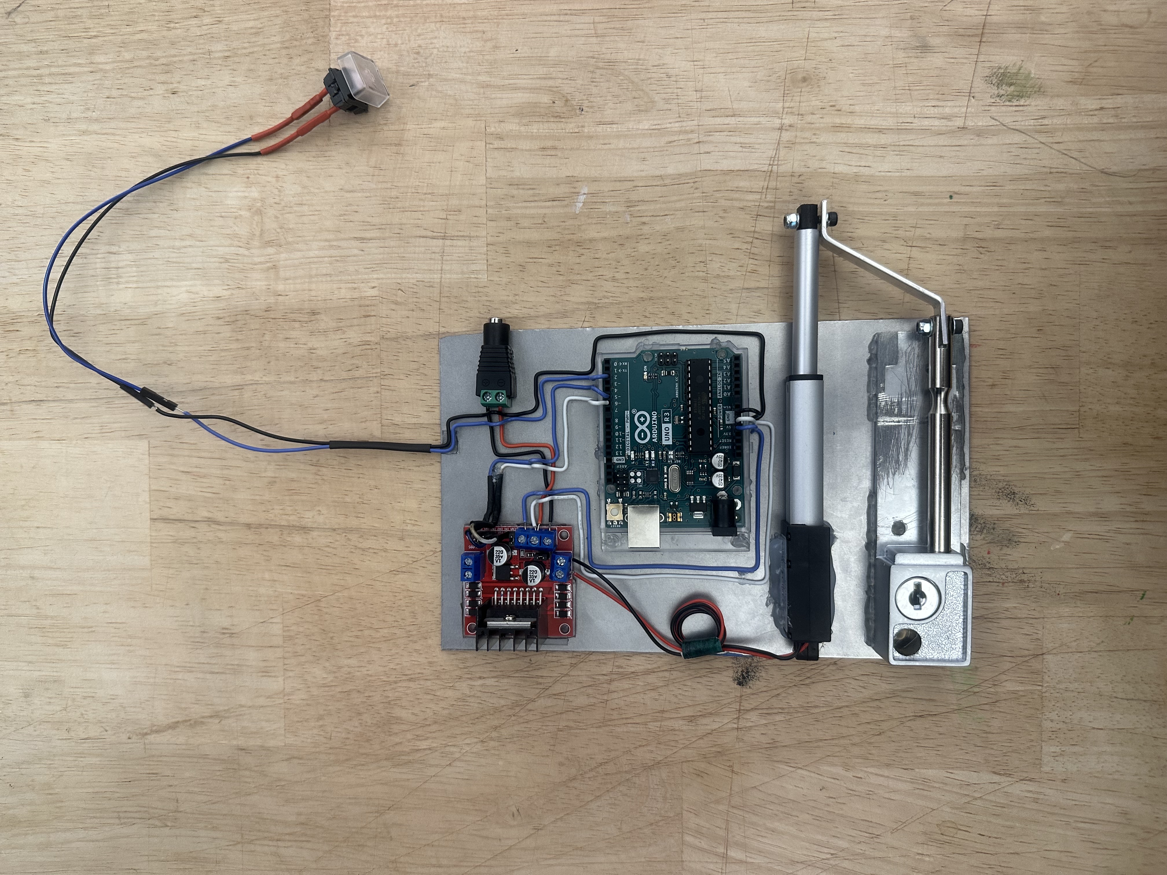 The finished lock plate on a workbench, with the push button on a long wire